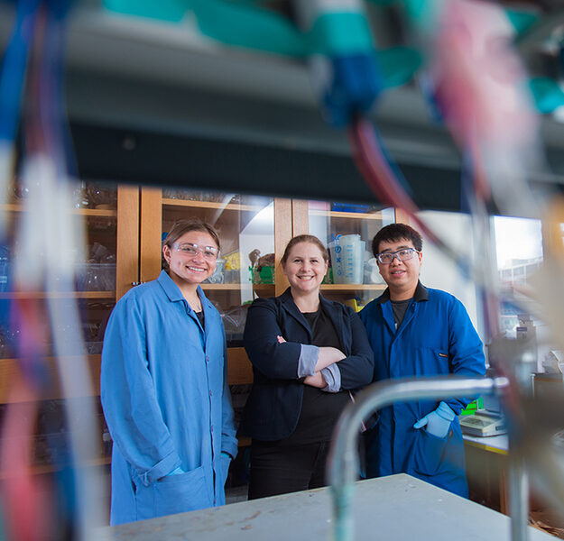 Ariel Furst and two graduate students stand together in a lab